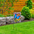 Wrought iron garden flag stand with colorful butterfly and welcome garden flag on green lawn.