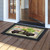 St Pat's Pickup Doormat with green plaid border and black pickup truck design on wooden floor.