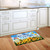 God Bless Our Home doormat with sunflowers on a kitchen floor beside white cabinets.