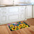 American Sunflowers Doormat with USA flags on a wooden kitchen floor beside white cabinets.