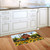 Sunflower Barn Doormat with vibrant sunflowers and rustic barn on a kitchen floor beside white cabinets.