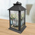 Black metal Farmhouse Jars Lantern with floral design on a wooden table with gingham background.