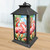 Black metal Flamingo Pair Lantern with pink flamingos and floral design on a wooden table indoors.