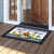 Country Home Sweet Home doormat with birdhouse design on wooden porch in front of open door.