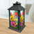 Black metal lantern with colorful butterflies and daisies design on glass panels, vibrant floral pattern.