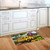 Yellow truck and sunflower design on a colorful Flower Farm Doormat on a wooden kitchen floor.