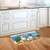 5 O'clock Beach Gnomes colorful doormat on wooden kitchen floor by white cabinets and sink.
