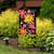 Vibrant Spring Fling Garden Flag with colorful flowers on black background, hanging on a garden stand.