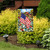 American Flower Field Garden Flag with USA flag and floral design on a garden stand outdoors.
