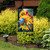 Birds in the Garden flag with sunflowers and colorful birds on a garden stand outdoors.