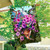 Hummingbirds and Petunias house flag with vibrant purple flowers and colorful hummingbirds in a hanging basket.