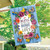 Bless This Home With Love House Flag with floral design and butterflies on blue wooden background.
