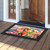Sunset Parrot doormat with colorful parrots, flowers, and tropical leaves on wooden porch outside doorway.