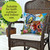 Floral Birdhouses Indoor/Outdoor Pillow on a wicker chair with colorful bird and butterfly garden design.