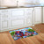 Home of the Free Birdhouses Doormat on wooden floor in front of white kitchen cabinets.
