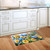 Bluebirds and Roses doormat on wooden floor in front of white kitchen sink and cabinets.
