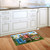 In the Garden Doormat on wooden kitchen floor beside white cabinets with colorful floral design.