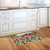 American Flower Field Doormat on wooden floor in front of white kitchen cabinets and sink.