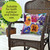 Pansies floral pillow on wicker chair, vibrant purple, pink, orange, and blue pansy flowers design.