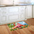 Flamingo pair design doormat on wooden floor in front of white kitchen cabinets and sink area.