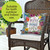 Bless This Home With Love Indoor/Outdoor Pillow on wicker chair with floral design and white cushion.