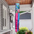 Springtime Hummingbirds Windsock Wind Twister with pink, blue and hummingbird design hanging from a porch.