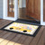 Happy Easter Pickup doormat with colorful Easter eggs on a wooden porch outside an open door.