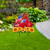 Red metal art truck with American flag and sunflowers on green lawn with stone path nearby.