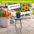 Black metal With God Plant Stand with colorful mosaic top and potted plant on a patio.