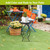 Black metal Home Plant Stand with plant and basket on green turf outdoor setting.