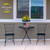 Wooden American Flag medium planter with yellow flowers on outdoor table between two black metal chairs.