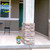 Small Sunshine Butterflies planter with flowers on a front porch next to a pillar and chair.