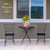 Flamingo Pair Medium Planter with yellow flowers on a small black metal table between two chairs.
