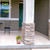 Small Flamingo Pair Planter on a porch next to a pillar and chair near green door.