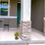 Sunflower Barn Small Planter on a porch with yellow flowers and a decorative stone pillar nearby.