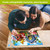 Couple assembling Briarwood Lane Floral Birdhouses 1000 Piece Jigsaw Puzzle on wooden floor together.