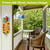 Cardinals and Sunflowers Metal Thermometer with vibrant design on a porch wall beside wicker chairs.