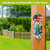 American Cardinal metal thermometer with floral design and American flag mounted on a wooden post.