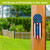 Wooden flag metal thermometer with American flag design mounted on a wooden post outdoors.
