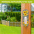Checkered sunflowers metal thermometer on wooden post, black and white checkered with yellow sunflowers design.