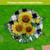 Round glass birdbath with checkered sunflowers and birds design on green grass background.