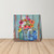 Vibrant flowers in colorful glass jars on a wooden shelf against a rustic blue background canvas art.