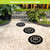 Black rubber stepping stones with "HOME" design on white pebbles in a garden pathway setting.