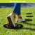 Black rubber stepping stones with green design on grass under yellow shoes.