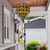Sunflowers Hot Air Balloon Spinner, yellow and black, hanging from a house porch roof outdoors.