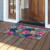 Pink and blue tropical floral coir doormat, 18 x 30 inches, on a wooden porch.