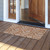 Brown coir doormat with white floral pattern, 18 x 30 inches, at a wooden entrance doorway.