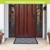Large gray paisley doormat with flocked design on front porch with brown wooden door.