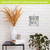 Metal wall decor with "HOME" and green wreath, on white brick background, small size.