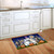 Costumed gnomes doormat on wooden floor in front of white kitchen cabinets with Halloween design.